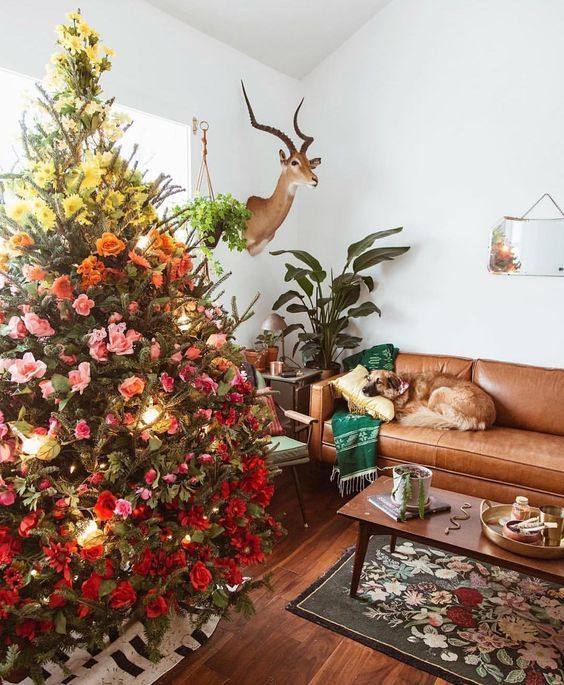 a fantastic gradient Christmas tree decorated with yellow, pink and red blooms and leaves plus lights is lovely