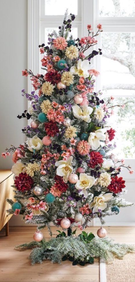 a flocked Christmas tree decorated with blooms and blooming branches, with blush ornaments and some dark foliage looks lovely