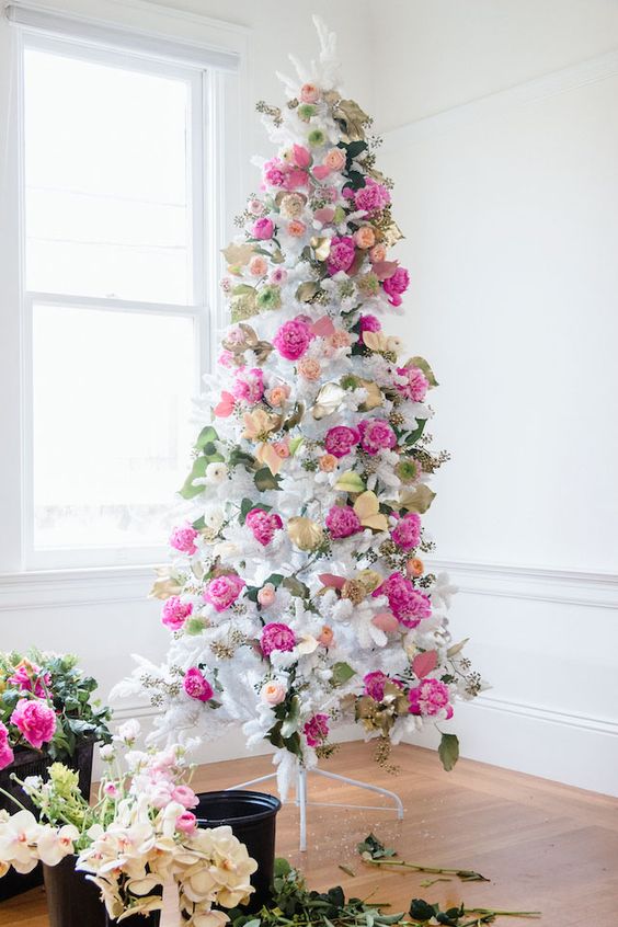 a romantic white Christmas tree decorated with hot pink and blush blooms, leaves and gilded foliage is super elegant