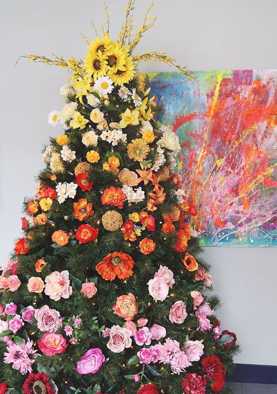 a super bold gradient Christmas tree decorated with faux blooms from yellow to deep red and with lights is beautiful