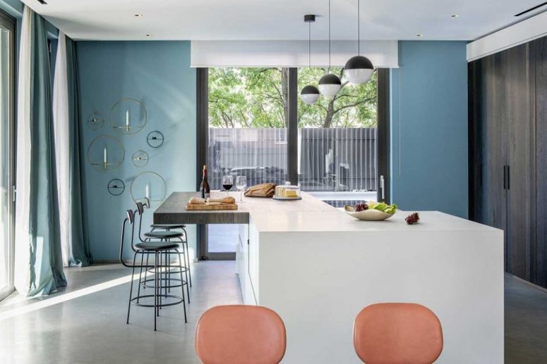 The kitchen is done with dark wooden storage units instead of traditional cabinets, and a large kitchen island with a bar zone