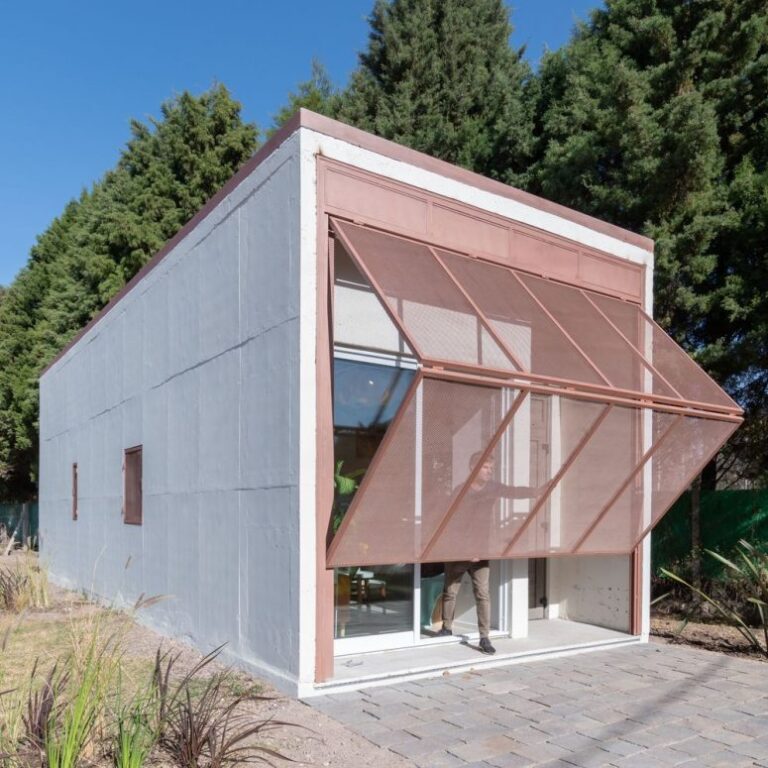 This small prefab home features a large folding screen that is a layer of protection to the house