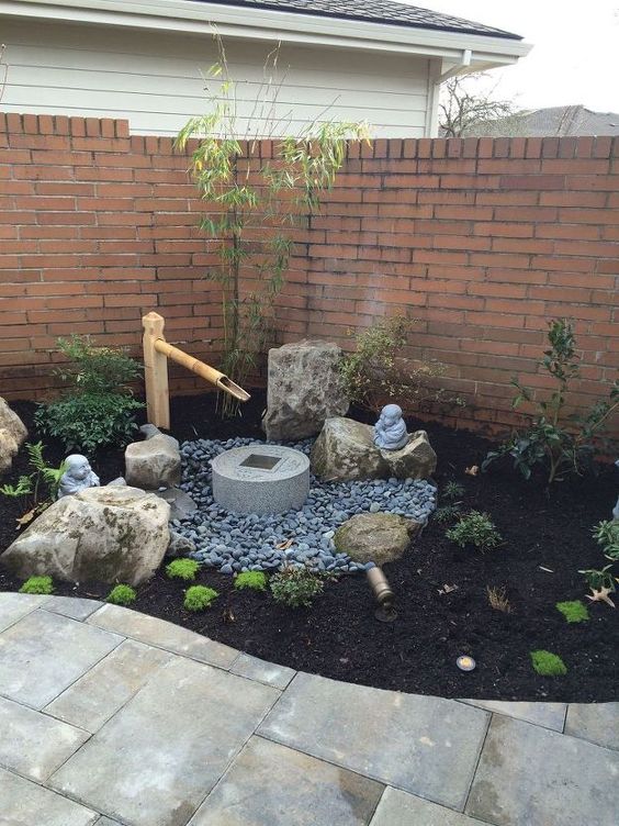 a small Japanese front yard with pebbles, greenery, a stone and bamboo fountain, rocks, shrubs is a lovely space